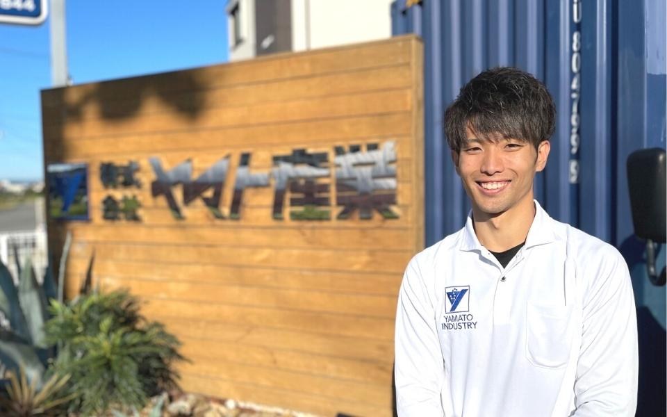 会社看板の前に立つ若手スタッフ
