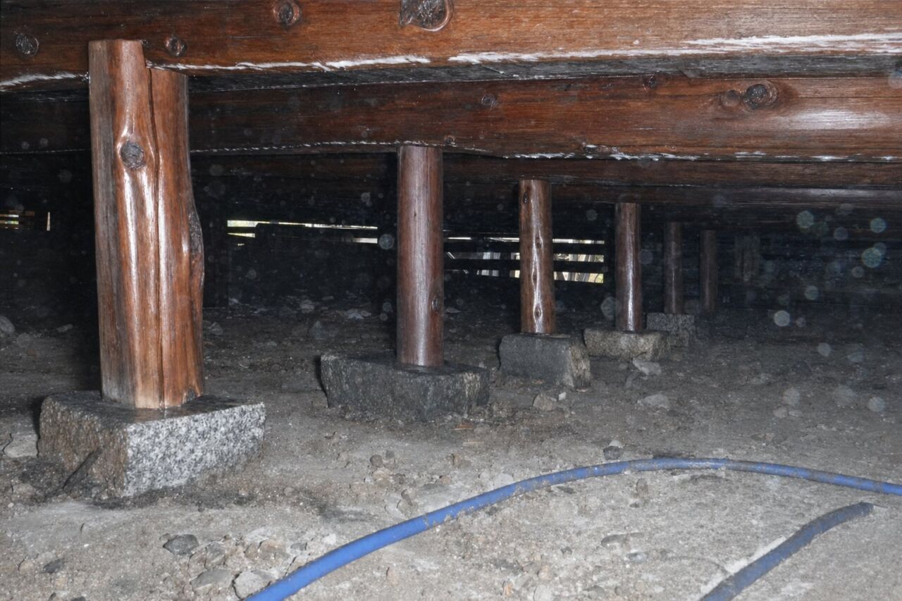 束石の上に柱が並ぶ古い木造建築の床下